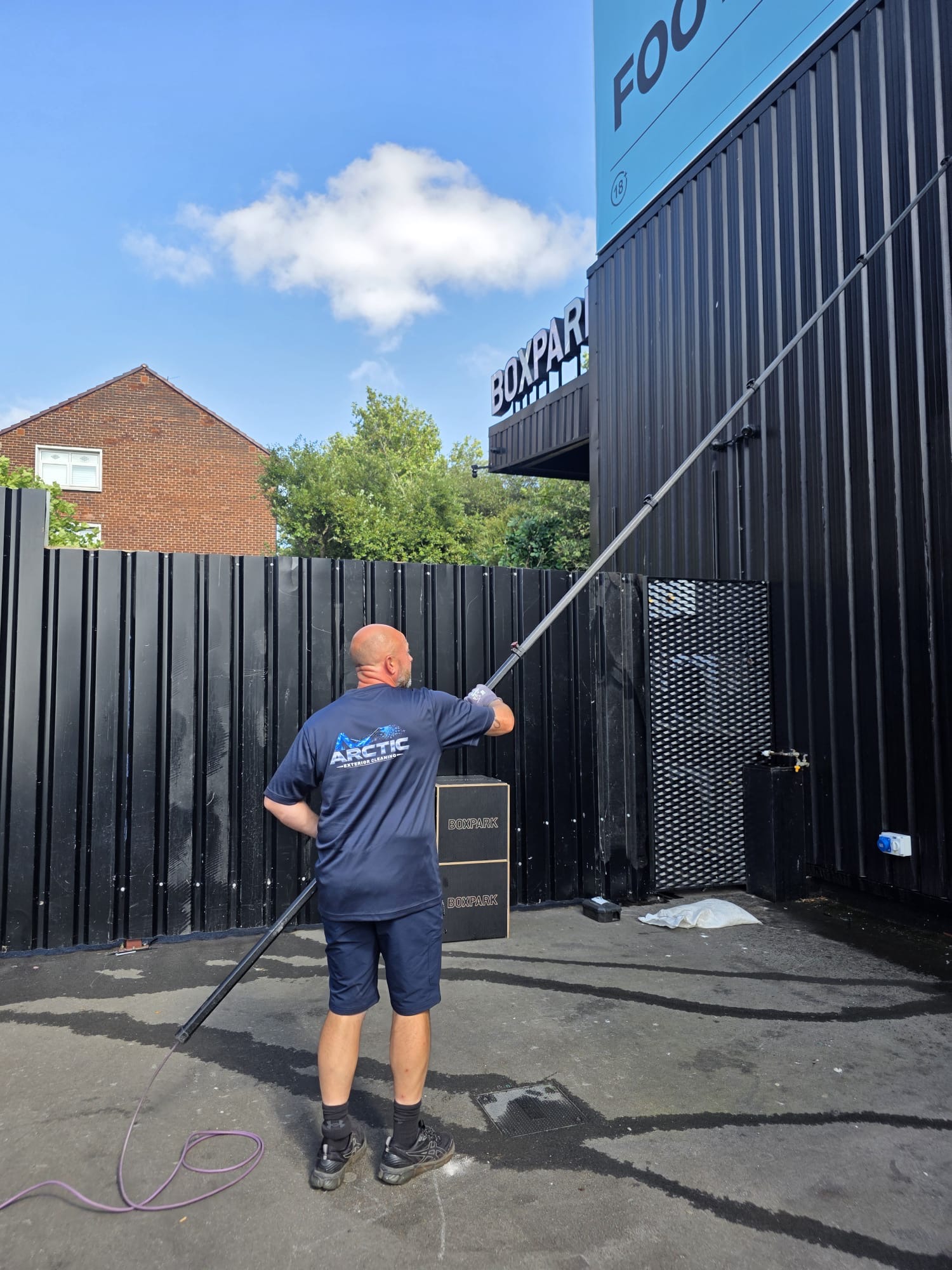 Uniformed Arctic Exterior Cleaning technician window cleaning with a water-fed pole system