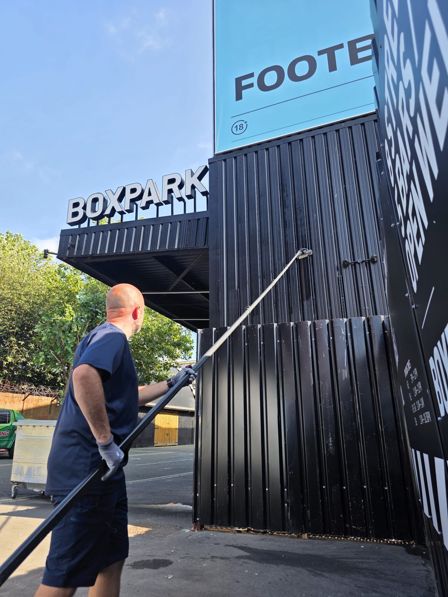 Arctic Exterior Cleaning technician using a water-fed pole to clean cladding at a commercial venue
